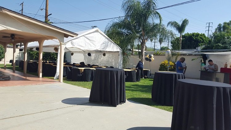 Backyard party setup with tables and chairs, ready for a celebration. Explore party tent rentals.